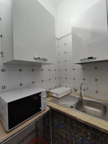 a kitchen with a microwave and a sink at Lolli Station House in Palermo