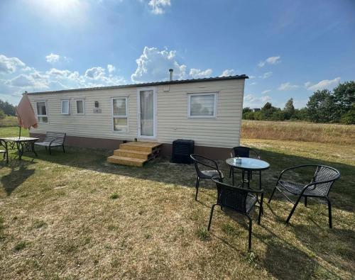 a caravan with a table and chairs in a yard at FarmaKolonia in Jamielnik