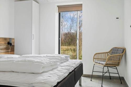 a bedroom with a bed and a chair and a window at 0364-Romo-Vestergardsvaenget-7 in Høm