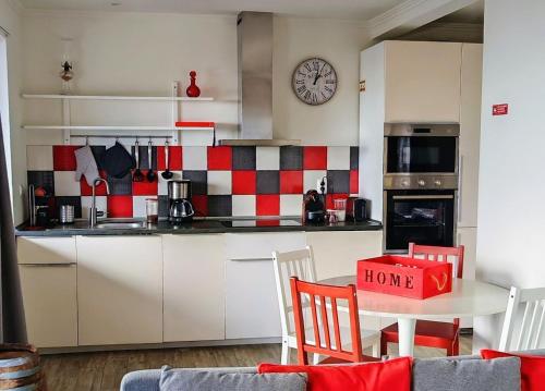 a kitchen with a red and white checkered wall at Casinha de Nesquim in Calheta de Nesquim