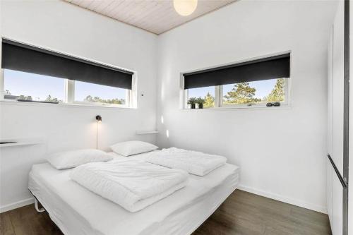a white bedroom with two windows and a bed at 0323-Romo-Vestergade-359 in Høm