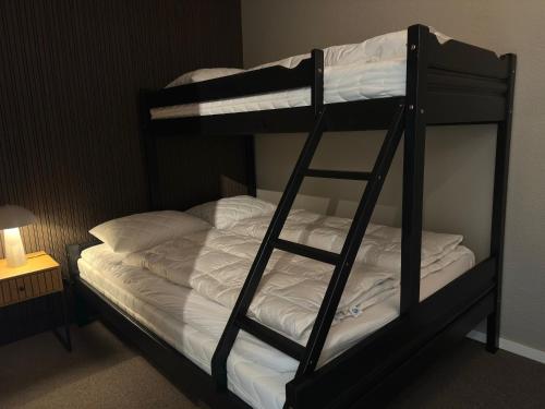 a black bunk bed with white sheets and a ladder at Leilighet på Hovden in Bykle