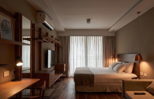a hotel room with a bed and a television at AQ Tailored Suites in Buenos Aires