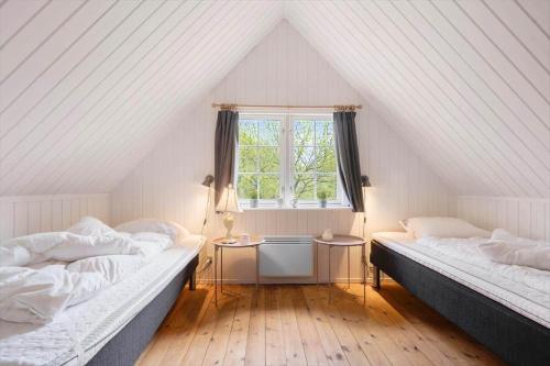 a attic room with two beds and a window at 0496-Romo-Norre-Frankel-9 in Høm
