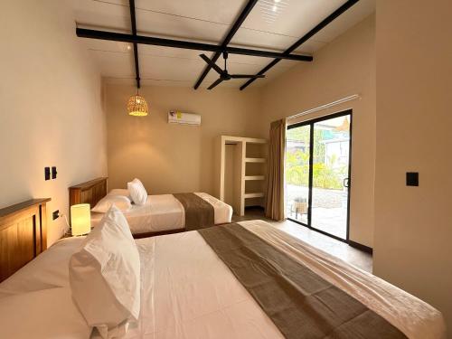a bedroom with two beds and a large window at Lalola de Puerto in Puerto Viejo
