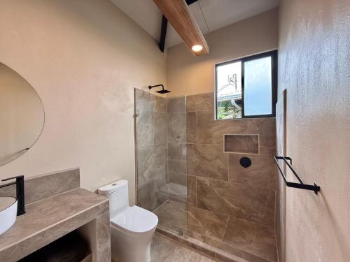 a bathroom with a shower and a toilet and a window at Lalola de Puerto in Puerto Viejo