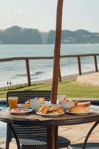 a table with plates of food on it with the beach at El Aram Natal Mar in Natal