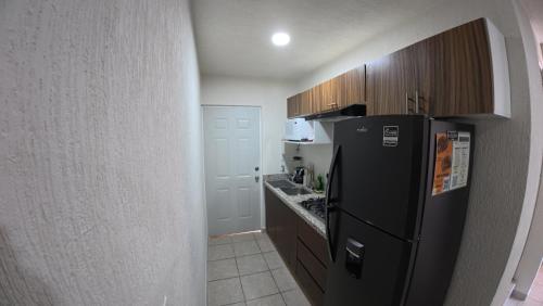 a kitchen with a black refrigerator and wooden cabinets at Departamento Belinda in Ixtapa