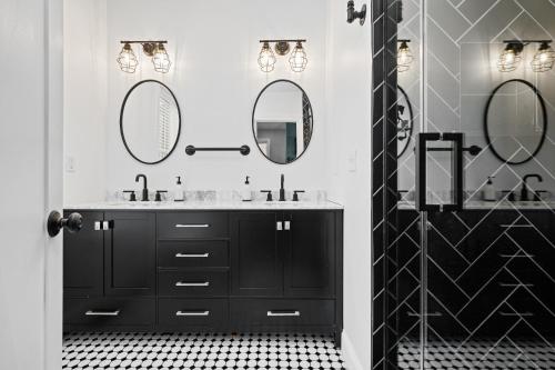 a black and white bathroom with two sinks and mirrors at Luxurious Design Easy Access to Downtown Pittsburgh Sleeps 4 in Pittsburgh