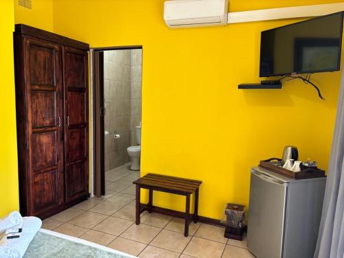 a yellow bathroom with a toilet and a tv on the wall at Spring Day in Piet Retief