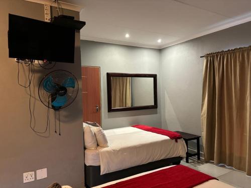 a bedroom with a bed with a fan and a mirror at Spring Day in Piet Retief