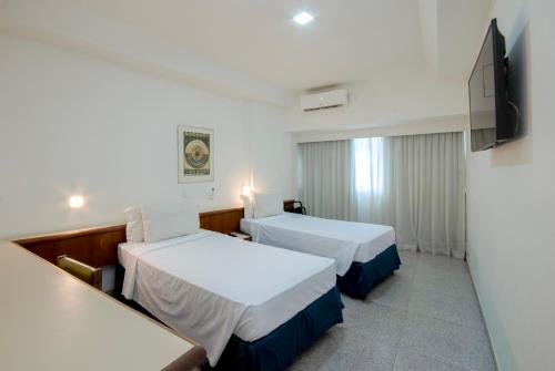 a hotel room with two beds and a flat screen tv at Hotel Bandeirantes in Rio de Janeiro