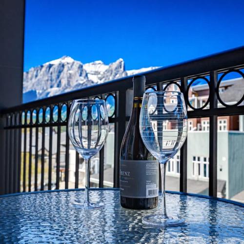 two wine glasses on a table with a bottle of wine at Westwinds - Funky Basecamp in the Rockies in Canmore