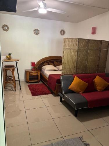 a bedroom with a bed and a couch and a table at Domaine de Locastel 2 in Morne-à-lʼEau