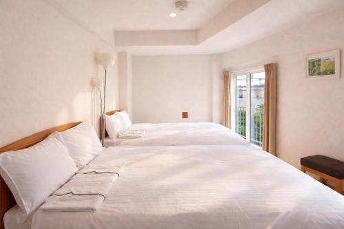 a white bed in a room with a window at Sakura Hotel Hatagaya in Tokyo