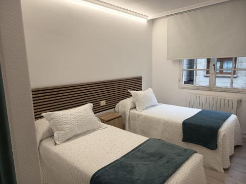 a room with two beds and a window at Apartamentos Demar Luis Casais in O Grove