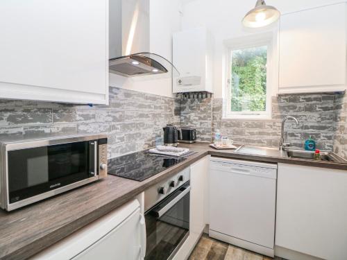a kitchen with white cabinets and a microwave at High Tor in Matlock