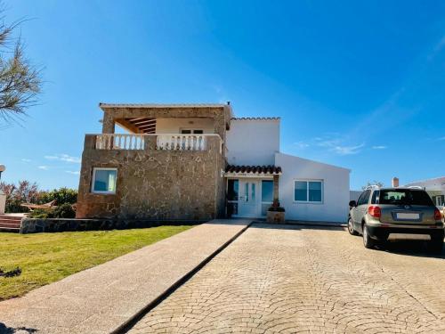 a house with a car parked in front of it at Villa Miramar Vistas espectaculares in Es Mercadal