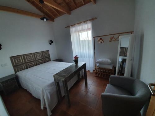 a bedroom with a bed and a table and a chair at Casas do Lourenço in São Roque do Pico