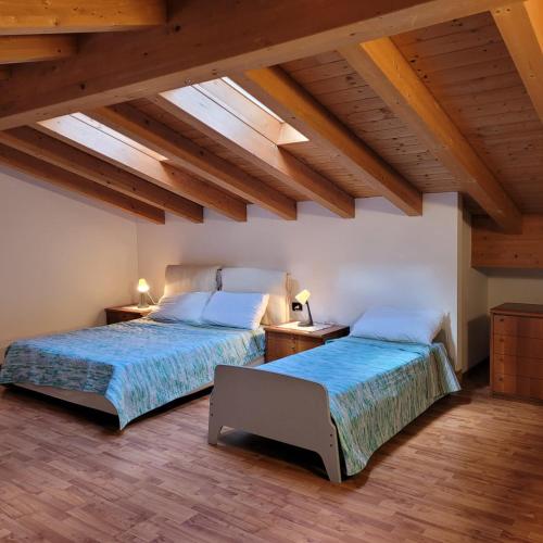 two beds in a room with wooden ceilings at Casa Gioia Alpina Mountain Lake Iseo Hospitality in Bossico