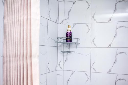 a bathroom with white tiled walls and a soap bottle on a shelf at Revitalize in Springs