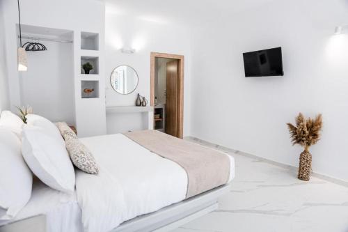 a white bedroom with a bed and a tv at Mylos Design Suites in Perissa