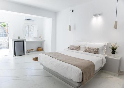 a white bedroom with a large bed with white walls at Mylos Design Suites in Perissa