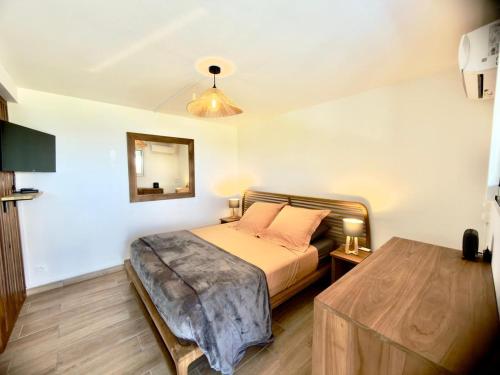 a bedroom with a bed and a mirror on the wall at Sunset View - Panoramic Sea View - Deshaies in Deshaies