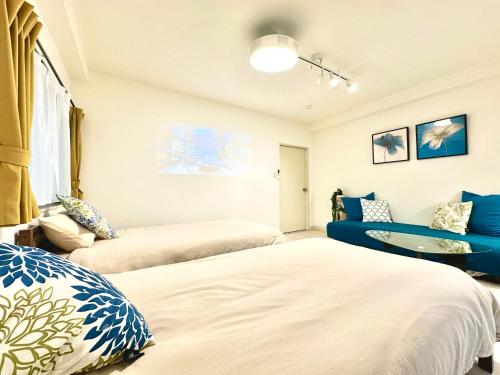 a bedroom with two beds and a blue couch at Villa Kokubunji Stay in Kokubunji
