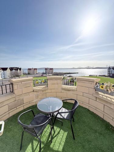 a patio with two chairs and a table on the grass at Penthouse at the Bay near Edinburgh in Saint Davids