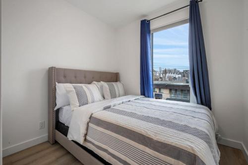 a bedroom with a bed and a large window at Exquisite 2 Bed Condo near DT Core WFree Parking in Calgary