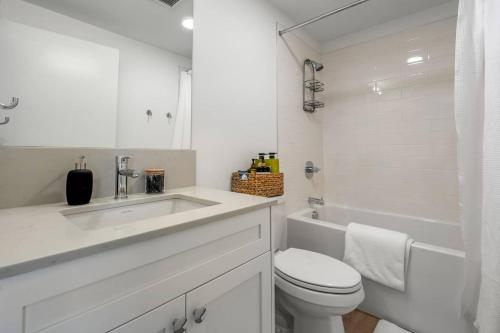 a white bathroom with a sink and a toilet at Exquisite 2 Bed Condo near DT Core WFree Parking in Calgary