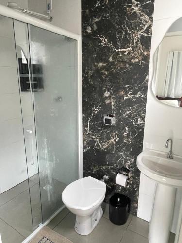 a bathroom with a toilet and a glass shower at Pousada 4 Estações in Canoinhas