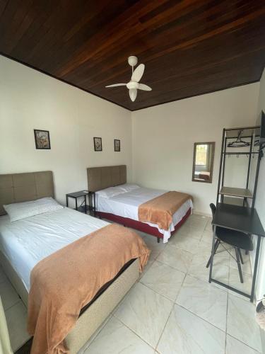 a bedroom with two beds and a ceiling fan at Pousada 4 Estações in Canoinhas
