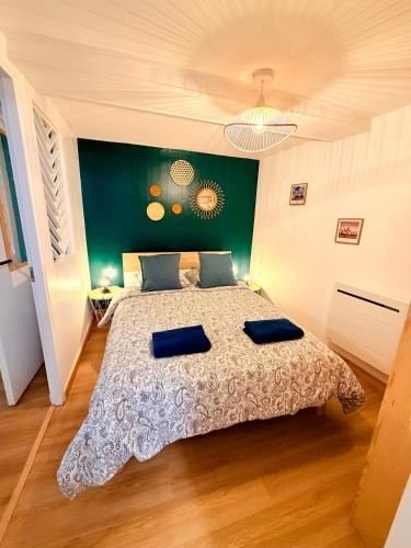 a bedroom with a bed with two blue pillows on it at Le Beau Dolois - Appartement Climatisé au Coeur de DOLE avec Parking GRATUIT à proximité in Dole
