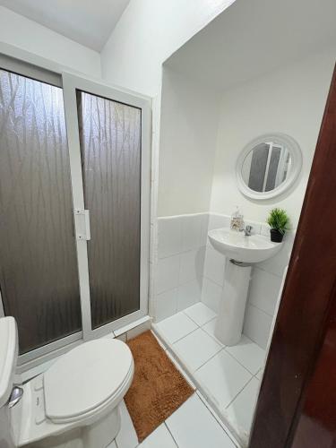 a white bathroom with a toilet and a sink at Casa Herminia in Omoa