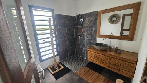 a bathroom with a shower with a sink and a mirror at Koa Lodge style Bali avec jacuzzi in Saint-Joseph