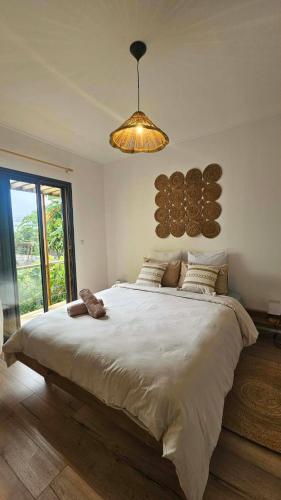 a bedroom with a large white bed with a light at Koa Lodge style Bali avec jacuzzi in Saint-Joseph