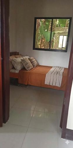 a bed sitting in a room with a window at Moalboal Homestay VILLA in Tomonoy