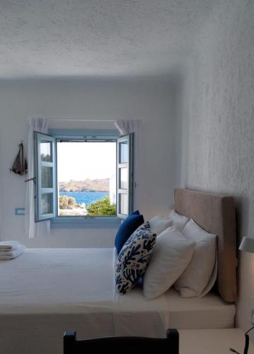 a bedroom with a bed with a large window at Traditional dream myconian studio in Ornos