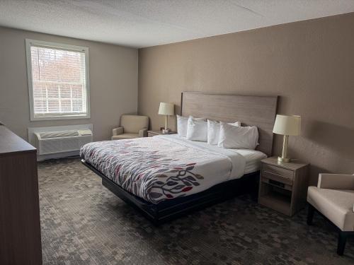 a hotel room with a bed and a chair at Whalers Inn and Suites in New Bedford