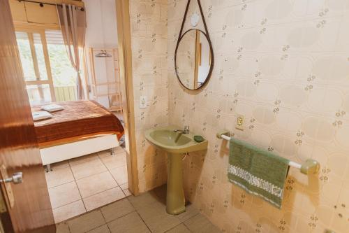 a bathroom with a sink and a mirror and a bed at IKE Hospedagem Uruguaiana - CENTRO in Uruguaiana