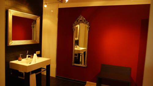 a bathroom with a sink and a mirror on a red wall at Gersthofer Auszeit in Gersthofen