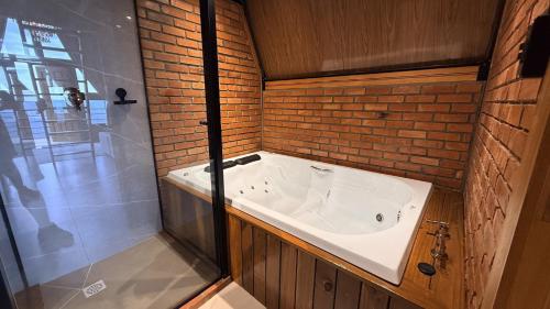 a bathroom with a tub and a glass shower at Refúgio em Gramado | cabana c/ hidromassagem in Gramado