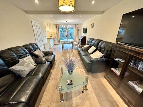 a living room with a leather couch and a table at Bright 3 bed House,FREE parking,Garden,nr seafront in Brighton & Hove