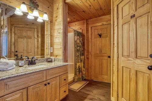 a bathroom with a sink and a large mirror at Bear Hug Cabin Gatlinburg Convenient to Everything! in Gatlinburg
