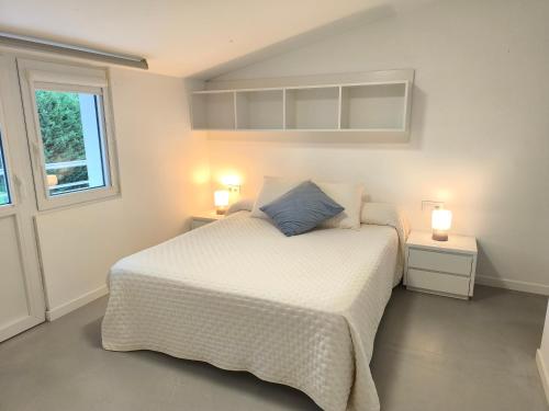 a bedroom with a bed with two night stands and two lamps at Atico Deluxe en Vimianzo in Toja