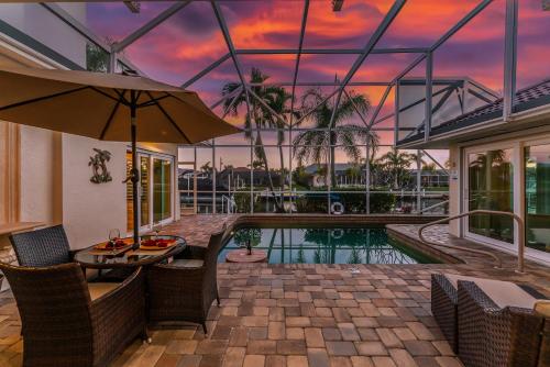 a house with a pool and a table with an umbrella at Villa Hibiscus-Waterfront-Free Heated Pool-Dock-Bikes-Other Amenities in Punta Gorda