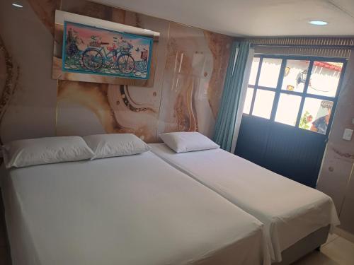 two beds in a small room with a window at Hostal Doña Betty 2 in Cartagena de Indias