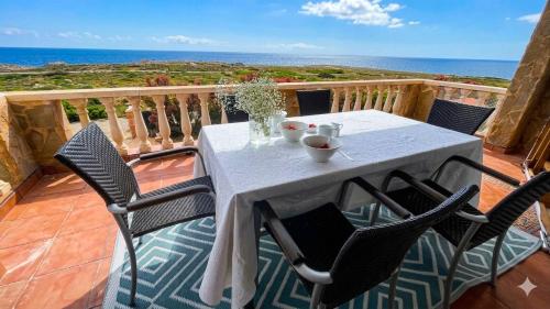 a table and chairs on a balcony with the ocean at Villa Miramar Vistas espectaculares in Es Mercadal